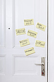 Adhesive notes on a front door with various reminders in German