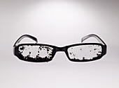 Dirty eyeglasses over gray background