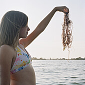 A teenage girl holding up seaweed