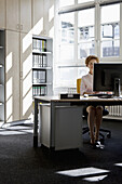 A businesswoman working at a desktop PC in an office