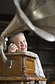 A woman with her eyes closed listening to a gramophone