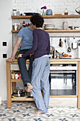 A mixed age couple kissing in their kitchen