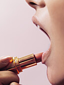 A woman applying lipstick, close-up of lips
