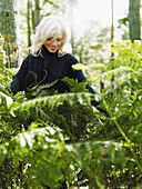 A smiling woman amongst lush foliage