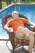 A retired senior man relaxing in the sun next to a pool