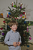 A young boy standing in front of a decorated Christmas tree