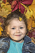 A young girl lying amongst autumn leaves