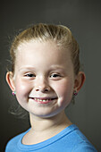 A grinning young girl wearing earrings