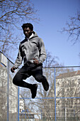 A serious young man jumping high in the air, Berlin, Germany