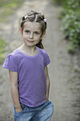 A young smiling girl standing on a dirt road