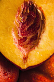 Half of a juicy peach resting on two uncut peaches, full frame