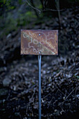 An old rusty sign with a skull and crossbones on it posted outdoors