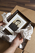 A man holding a picture wrapped in packing paper, focus on hands