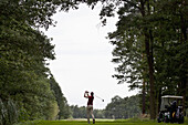 A female golfer teeing off, rear view