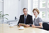 A businessman and businesswoman using a digital tablet in a meeting