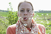 A woman blowing on a dandelion, close-up