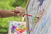 A child painting on an easel, close-up of hand