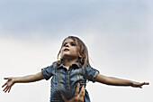 A hand holding up a young girl who is pretending to be an airplane