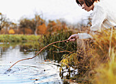 A woman poking at the water with a stick
