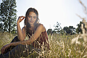 Girl sitting amongst timothy grass touching her hair