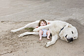 A baby lying with a dog