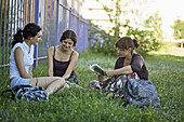 Two friends in a park listening to their friend read from a book