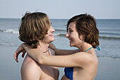 A young affectionate couple laughing at the beach