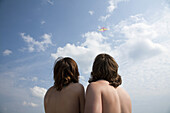 A young couple flying a kite, rear view