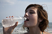 A woman drinking bottled water at the beach