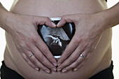 A pregnant woman holding an ultrasound printout against her belly