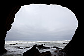 A cloudy overcast sky over the ocean seen from a darkened cave