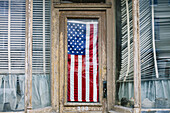 An American flag hanging in the door of a small business