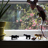 A line of miniature plastic toy animals on a window sill
