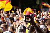 Detail of a person in a crowd holding a mobile phone