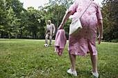 Senior couple play soccer in the park