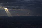 Sun streaming through storm clouds on landscape