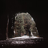 View of women walking towards bridge through cave