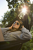 Teenager listening to music, lying in hammock