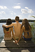 Group of friends sat on jetty looking at view