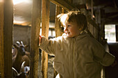 Baby girl standing in barn and smiling