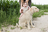 Woman holding baby girl on Portuguese Water Dog's back