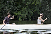 Young couple rowing canoe on lake