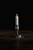 A lit candle in a silver candlestick holder