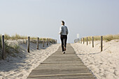 Mature woman jogging along boardwalk