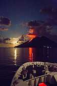 Bow of cruise ship MS Deutschland (Reederei Peter Deilmann) approaching Stromboli volcano with lava flow and moonrise, Mediterranean Sea, near Lipari, Aeolian Islands, near Sicily, Italy