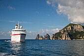 Cruise ship MS Deutschland (Reederei Peter Deilmann) passing Faraglioni Rocks and coastline, Isola di Capri, Campania, Italy