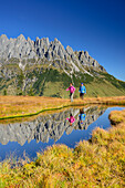 Man and woman hiking near a mountain lake with Mandlwand ridge at Hochkoenig in the background, Berchtesgaden range, Salzburg, Austria