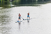 Men stand up paddling on the river Alster, Hamburg, Germany