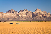 Sand and jeeps in front of the Idinen mountains in the libyan desert, Libya, Sahara, North Africa