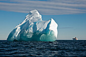 Iceberg in bright sunlight with expedition cruise ship MS Hanseatic (Hapag-Lloyd Cruises) in the background, Bird Point, Ross Island, Antarctica